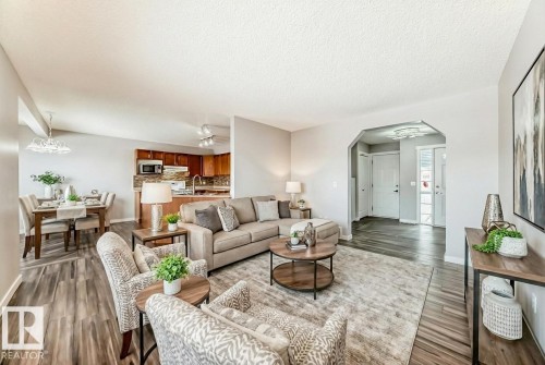 Living area with arched walkways, a textured ceiling, dark wood-style floors, and rail lighting - 3208 29 Avenue, Edmonton, AB - Indoor Photo Showing Living Room