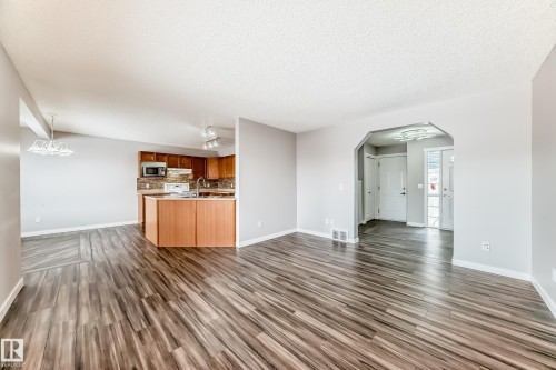 Unfurnished living room with arched walkways, dark wood finished floors, and a textured ceiling - 3208 29 Avenue, Edmonton, AB - Indoor Photo Showing Other Room