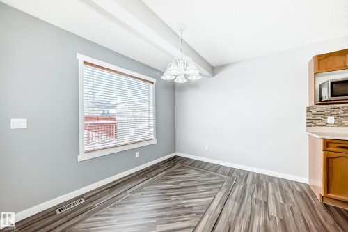 Unfurnished dining area with hanging lights and dark wood-style flooring - 3208 29 Avenue, Edmonton, AB - Indoor Photo Showing Other Room