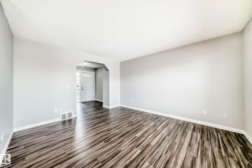 Unfurnished room with arched walkways, a textured ceiling, and dark wood-style flooring - 3208 29 Avenue, Edmonton, AB - Indoor Photo Showing Other Room