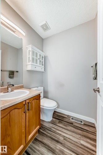 Half bath with vanity, dark wood-style floors, and a textured ceiling - 3208 29 Avenue, Edmonton, AB - Indoor Photo Showing Bathroom