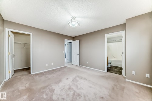 Unfurnished bedroom featuring light carpet, a spacious closet, a textured ceiling, and ensuite bathroom - 3208 29 Avenue, Edmonton, AB -  Photo Showing Other Room