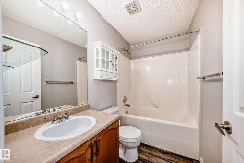 Bathroom with vanity, a textured ceiling, dark wood-style flooring, and shower / tub combination - 3208 29 Avenue, Edmonton, AB - Indoor Photo Showing Bathroom