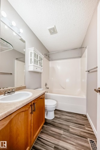 Full bath featuring vanity, a textured ceiling, shower / bathtub combination, and dark wood-style floors - 3208 29 Avenue, Edmonton, AB - Indoor Photo Showing Bathroom