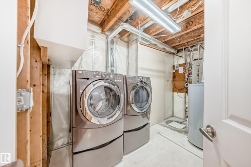 Laundry area featuring water heater, separate washer and dryer, and concrete flooring - 3208 29 Avenue, Edmonton, AB - Indoor Photo Showing Laundry Room