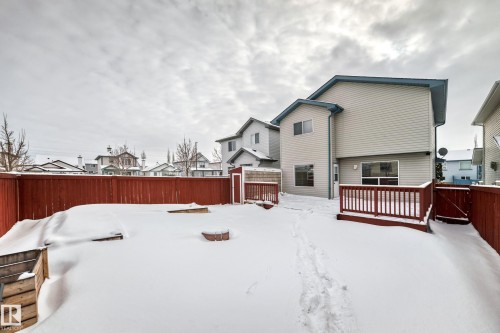 Snow covered back of property with a residential view, a fenced backyard, a wooden deck, and a gate - 3208 29 Avenue, Edmonton, AB - Outdoor With Deck Patio Veranda