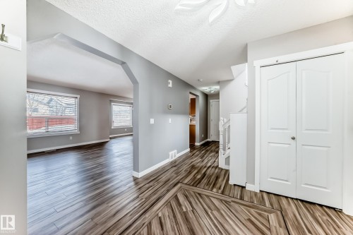 Unfurnished living room featuring a textured ceiling, dark wood-type flooring, and arched walkways - 3208 29 Avenue, Edmonton, AB - Indoor Photo Showing Other Room