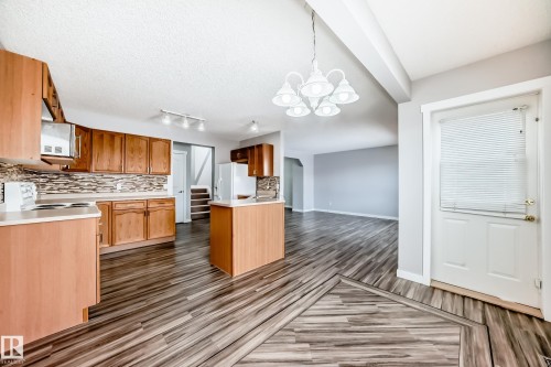 Kitchen featuring decorative backsplash, light countertops, hanging lights, white appliances, and a textured ceiling - 3208 29 Avenue, Edmonton, AB - Indoor Photo Showing Kitchen With Double Sink