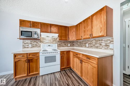 Kitchen featuring white range with electric stovetop, light countertops, a textured ceiling, backsplash, and dark wood-type flooring - 3208 29 Avenue, Edmonton, AB - Indoor Photo Showing Kitchen