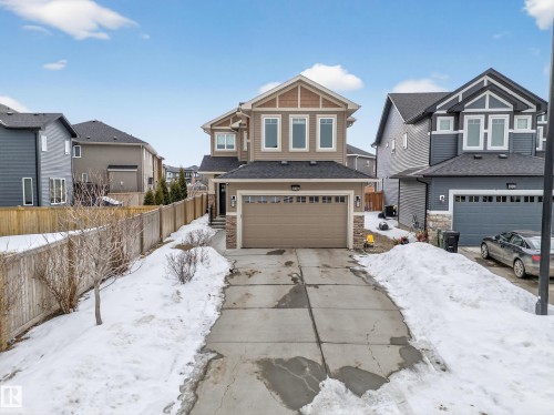 Craftsman-style house with stone siding, a garage, driveway, and a residential view - 1907 Adamson Terrace, Edmonton, AB - Outdoor