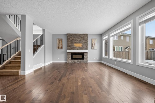 Unfurnished living room featuring dark wood finished floors, a textured ceiling, and a fireplace - 1907 Adamson Terrace, Edmonton, AB - Indoor Photo Showing Living Room With Fireplace