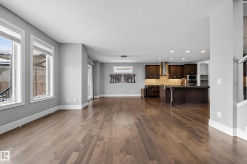 Unfurnished living room featuring dark wood-style floors, a textured ceiling, and recessed lighting - 1907 Adamson Terrace, Edmonton, AB - Indoor