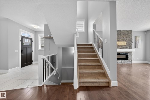 Stairs with plenty of natural light, hardwood / wood-style floors, a textured ceiling, and a fireplace - 1907 Adamson Terrace, Edmonton, AB - Indoor Photo Showing Other Room With Fireplace