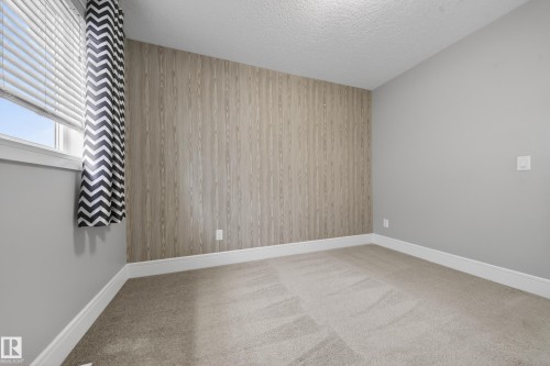 Spare room featuring wood walls, light colored carpet, a textured ceiling, and an accent wall - 1907 Adamson Terrace, Edmonton, AB - Indoor Photo Showing Other Room