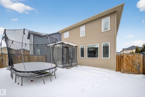 Snow covered rear of property with a trampoline, a fenced backyard, a gate, and a sunroom - 1907 Adamson Terrace, Edmonton, AB - Outdoor With Exterior