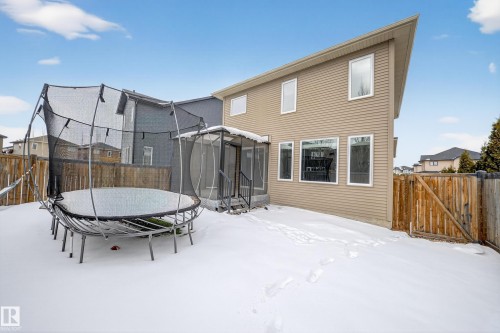 Snow covered rear of property featuring a trampoline, a fenced backyard, a gate, and a deck - 1907 Adamson Terrace, Edmonton, AB - Outdoor With Exterior
