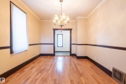 Spare room with a chandelier, light wood-style floors, and crown molding - 