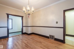 Empty room with a chandelier, crown molding, and light wood-style floors - 