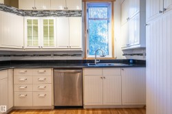 Kitchen featuring stainless steel dishwasher, backsplash, and glass insert cabinets - 