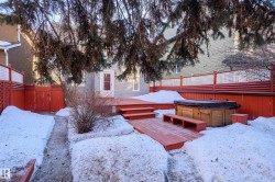 Snowy yard featuring a hot tub, a deck, and a gate - 