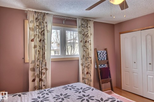 Bedroom featuring a textured ceiling, a closet, a ceiling fan, and light laminate  flooring - 4520 20A Avenue, Edmonton, AB - Indoor Photo Showing Bedroom