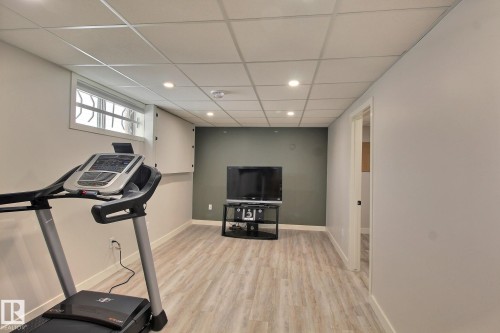 Living room featuring light wood-type flooring, a drop ceiling, and recessed lighting - 4520 20A Avenue, Edmonton, AB - Indoor Photo Showing Gym Room