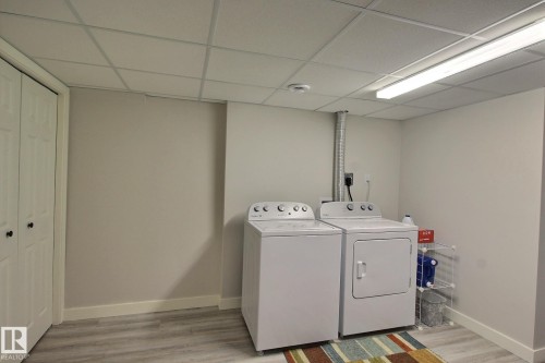 Separate Laundry area with a drop ceiling, light vinyl plank floors, and washer and clothes dryer - 4520 20A Avenue, Edmonton, AB - Indoor Photo Showing Laundry Room