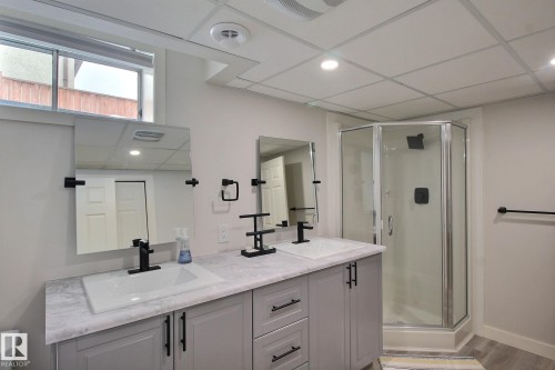 Bathroom with double vanity, a stall shower, recessed lighting, light vinyl plank floors, and a drop ceiling - 4520 20A Avenue, Edmonton, AB - Indoor Photo Showing Bathroom