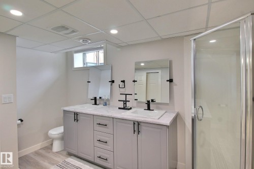 Full bathroom featuring double vanity, a shower stall, light vinyl plank flooring, recessed lighting, and a paneled ceiling - 4520 20A Avenue, Edmonton, AB - Indoor Photo Showing Bathroom