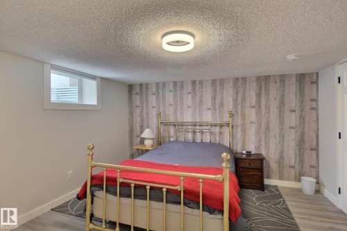 Bedroom featuring wood finished floors, a textured ceiling, and an accent wall - 4520 20A Avenue, Edmonton, AB - Indoor Photo Showing Bedroom