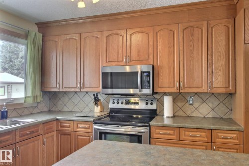 Kitchen featuring stainless steel appliances, wood finish cabinets, backsplash, and a textured ceiling - 4520 20A Avenue, Edmonton, AB - Indoor Photo Showing Kitchen