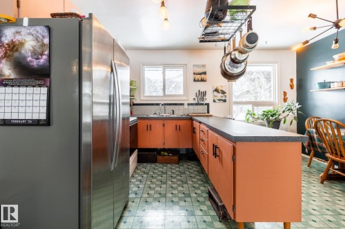 Kitchen with refrigerator, a peninsula, dark countertops, light flooring, and plenty of natural light - 12231 47 Street, Edmonton, AB - Indoor