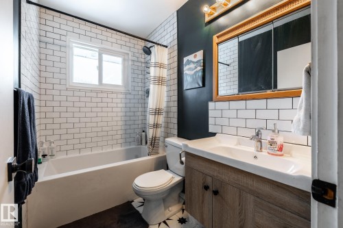 Bathroom featuring vanity, backsplash, tile walls, and shower/bath combo with shower curtain - 12231 47 Street, Edmonton, AB - Indoor Photo Showing Bathroom