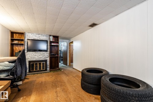 Family room in basement with built in shelves and fireplace, and unfinished floors - 12231 47 Street, Edmonton, AB - Indoor With Fireplace