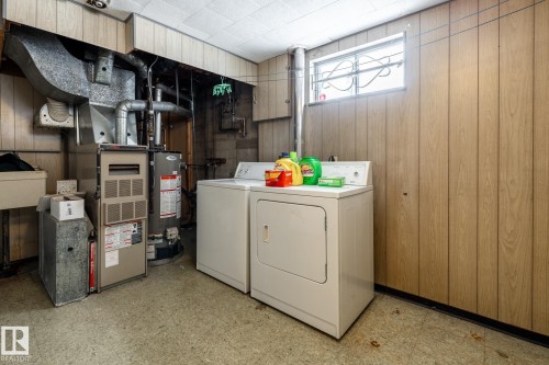 Laundry area featuring light flooring, wooden walls, independent washer and dryer, water heater, and furnace - 12231 47 Street, Edmonton, AB - Indoor Photo Showing Laundry Room