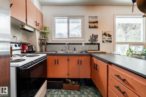 Kitchen featuring range with electric stovetop, open shelves, dark countertops, and stainless steel fridge - 12231 47 Street, Edmonton, AB - Indoor Photo Showing Kitchen With Double Sink