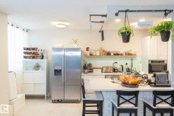 Kitchen featuring appliances with stainless steel finishes, a kitchen bar, open shelves, white cabinetry, and a center island with sink - 