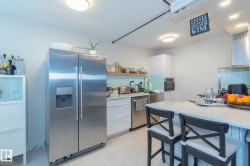 Kitchen with appliances with stainless steel finishes, white cabinets, open shelves, range hood, and light stone counters - 