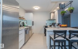 Kitchen featuring stainless steel appliances, white cabinets, exhaust hood, a breakfast bar, and recessed lighting - 