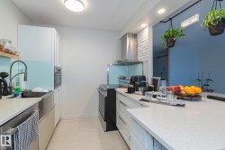 Kitchen with white cabinetry, exhaust hood, appliances with stainless steel finishes, light stone counters, and recessed lighting - 