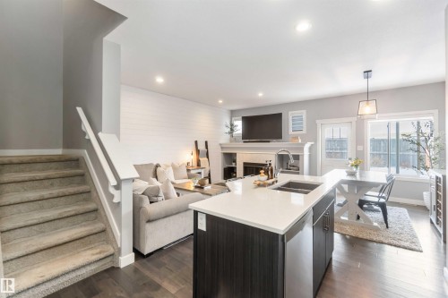 Kitchen with open floor plan, an island with sink, dark wood-style flooring, and hanging light fixtures - 17143 38 Street, Edmonton, AB - Indoor Photo Showing Kitchen With Fireplace With Double Sink