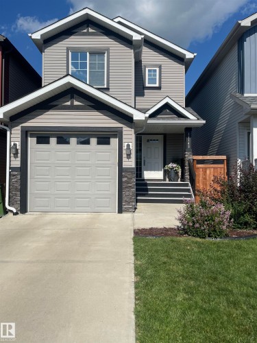 View of front of property with a porch, stone siding, concrete driveway, a front lawn, and an attached garage - 17143 38 Street, Edmonton, AB - Outdoor