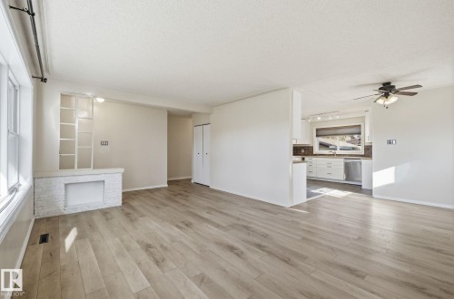 Unfurnished living room featuring ceiling fan, a textured ceiling, light wood finished floors, and rail lighting - 12107 53 Street, Edmonton, AB - Indoor Photo Showing Kitchen