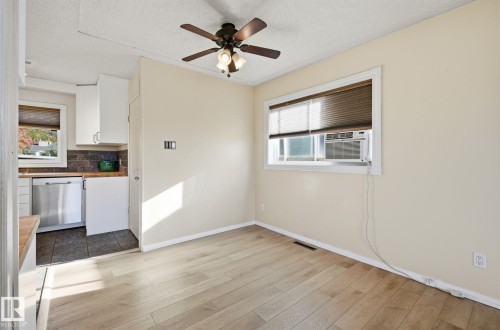 Unfurnished dining area featuring a textured ceiling, a ceiling fan, healthy amount of natural light, dark wood-style floors, and cooling unit - 12107 53 Street, Edmonton, AB - Indoor