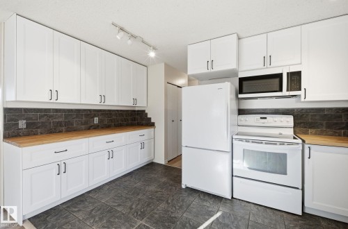 Kitchen featuring wooden counters, white appliances, white cabinetry, tasteful backsplash, and track lighting - 12107 53 Street, Edmonton, AB - Indoor Photo Showing Kitchen