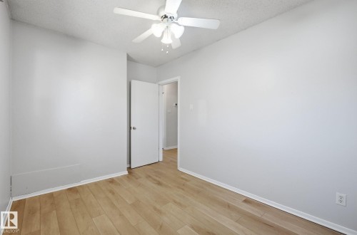 Unfurnished room featuring light wood-style floors, a textured ceiling, and ceiling fan - 12107 53 Street, Edmonton, AB - Indoor Photo Showing Other Room