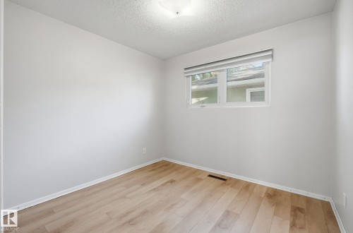 Unfurnished room featuring light wood-style floors and a textured ceiling - 12107 53 Street, Edmonton, AB - Indoor Photo Showing Other Room