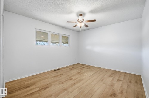 Spare room featuring light wood-style flooring, ceiling fan, and a textured ceiling - 12107 53 Street, Edmonton, AB - Indoor Photo Showing Other Room