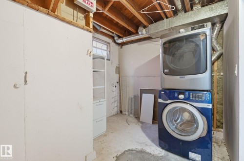 Laundry area with concrete flooring and stacked washer and clothes dryer - 12107 53 Street, Edmonton, AB - Indoor Photo Showing Laundry Room