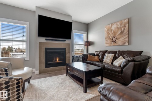 Living area featuring a tiled fireplace and light wood finished floors - 1043 South Creek Wynd, Stony Plain, AB - Indoor Photo Showing Living Room With Fireplace